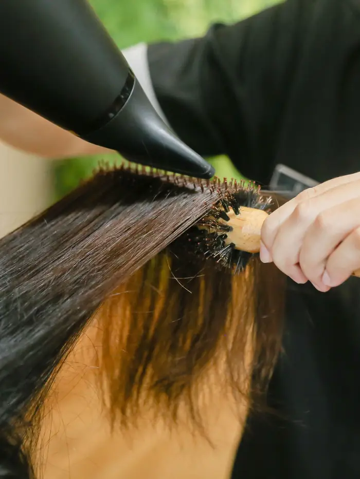 Stylist giving a blowout with a round brush